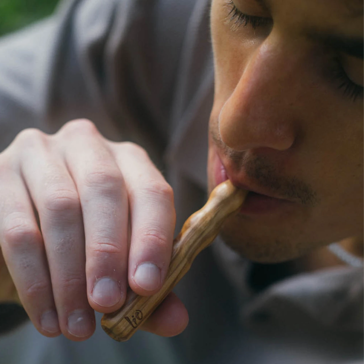 Hombre dando una calada a un difusor Lio de madera de olivo